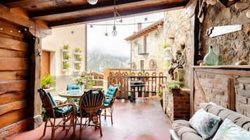 A cozy patio area with a round table, wicker chairs, and a cushioned sofa.