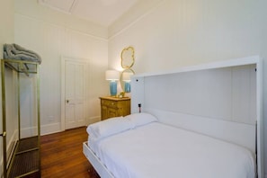 A bedroom with a bed, a wooden dresser, a mirror, and a door. - Austin (Mobile)