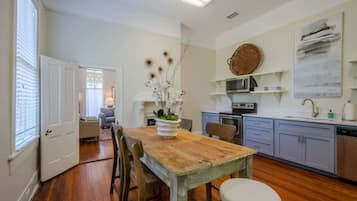 A kitchen with a wooden table, chairs, a vase of flowers, and modern appliances.