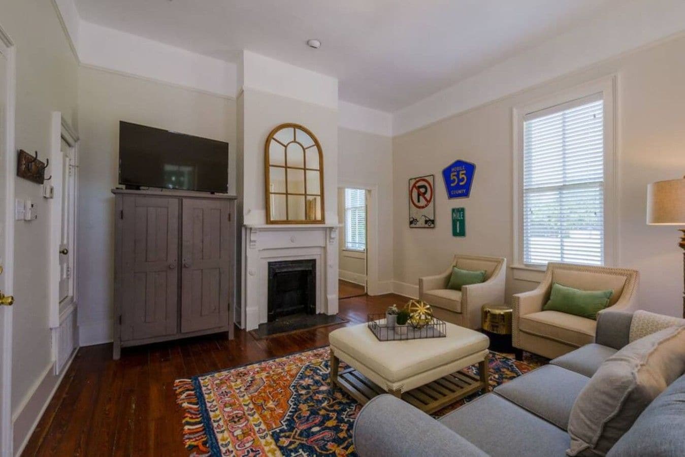 A living room with a fireplace, a television, a sofa, and a patterned rug.