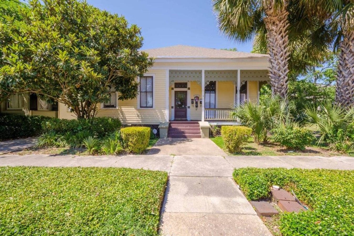 A two-story house with a front porch, a driveway, and well-maintained landscaping.