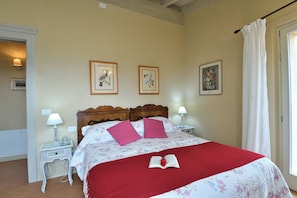 A bedroom with a wooden headboard, two bedside tables with lamps, a floral bedspread, and a red blanket. - Il Mirto - 3 Bedroom villa, pool & AC by Pelagone Golf, Gavorrano near the coast (Gavorrano)