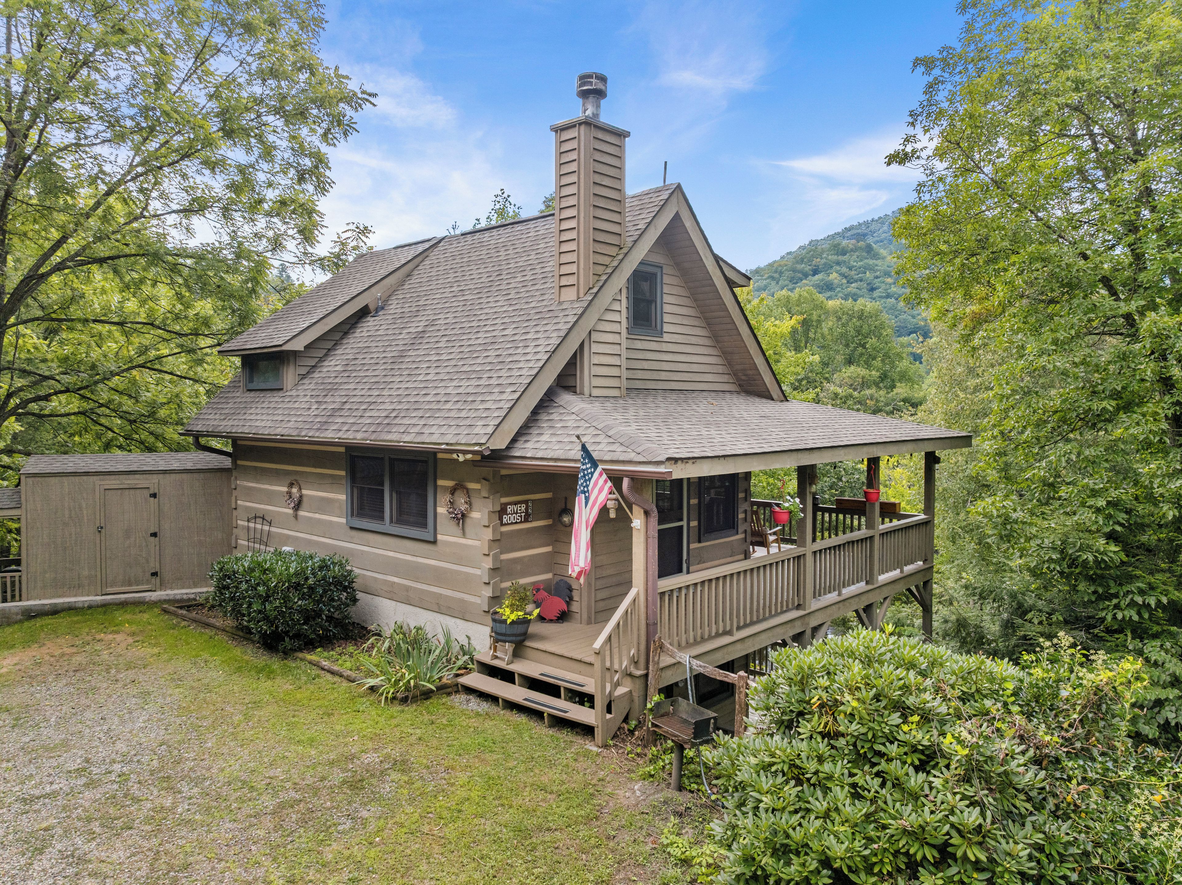 Une maison à deux étages avec un porche, une cheminée et un drapeau américain.