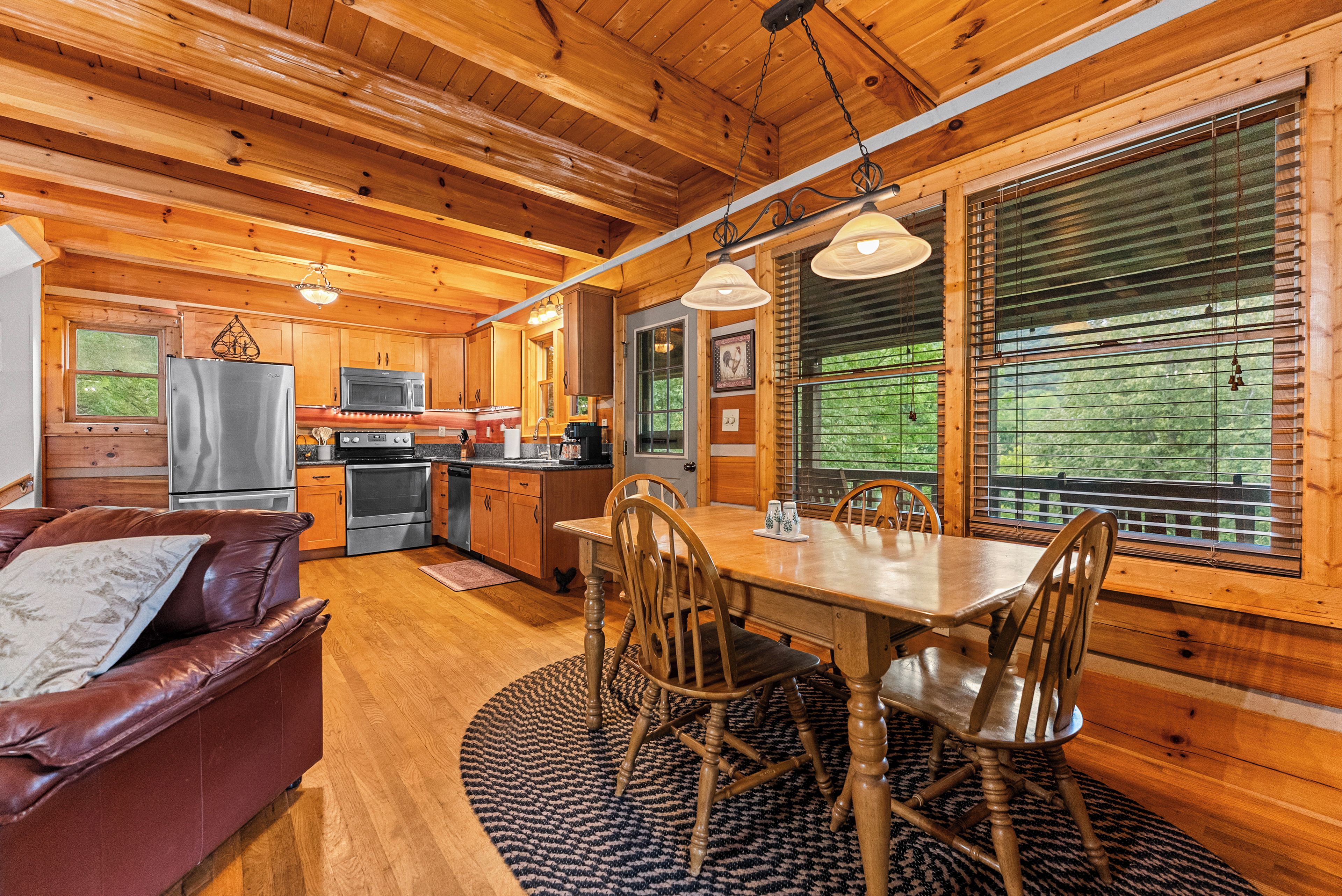 L’intérieur d’un chalet en bois comprend une table à manger, des chaises, un coin cuisine et un canapé en cuir.