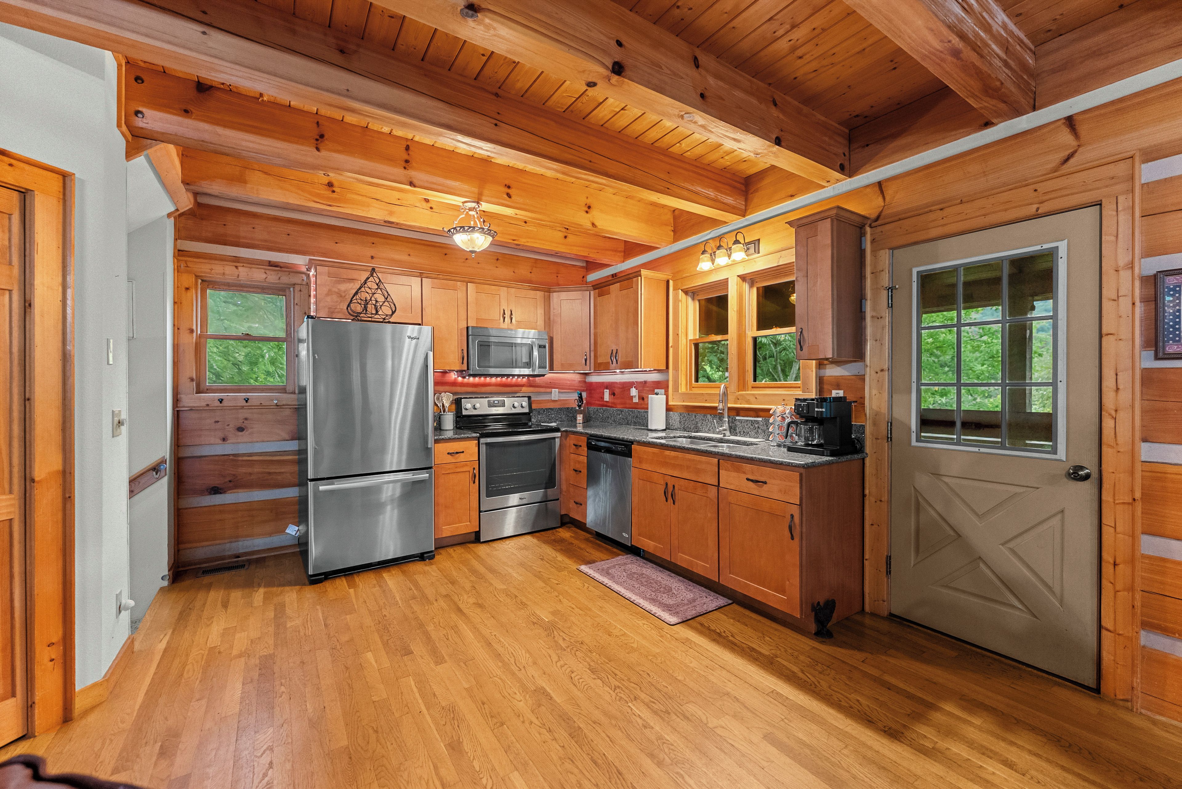 Une cuisine aménagée dans une cabane en bois, équipée d’un réfrigérateur, d’un four à micro-ondes, d’une cuisinière et d’un évier.