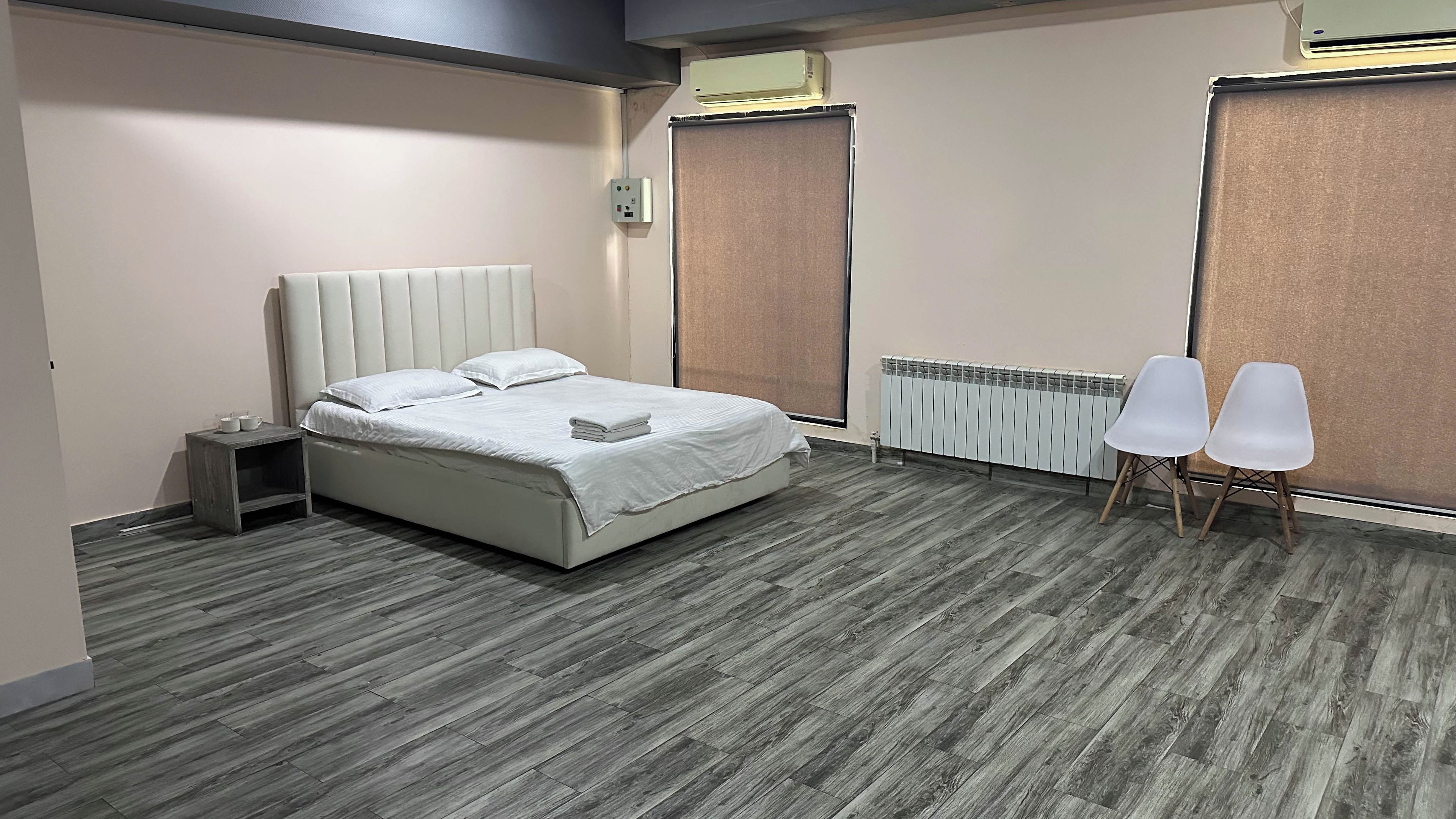 Una habitación de hotel moderna con cama, mesita de noche y dos sillas.