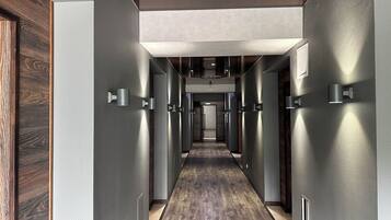 Un pasillo moderno con suelo de madera, paredes metálicas e iluminación empotrada.