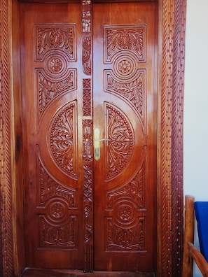 A wooden double door with intricate carvings and a central handle.