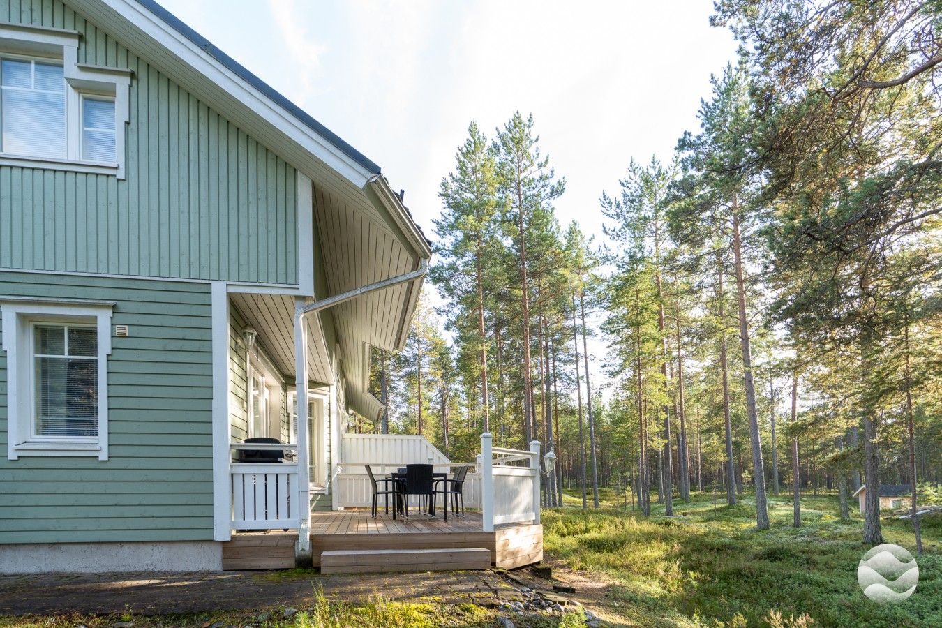 Talo, jossa on kuisti, ulkotila istumiseen ja metsäinen alue.
