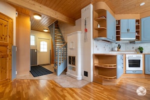 A wooden interior with a kitchen, a staircase, and a door leading to another room.