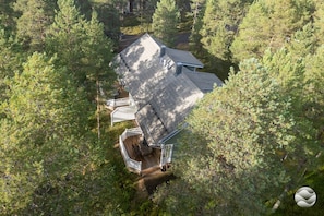 A house surrounded by dense forest, with a visible deck and a chimney.