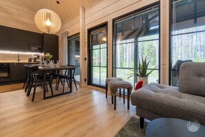 Ein modernes Interieur mit Essbereich, Küche und Sitzgelegenheit, versehen mit großen Fenstern.