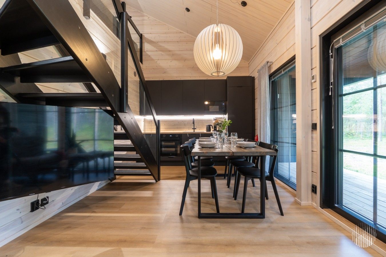 Una cocina moderna con comedor, piso de madera y una escalera.
