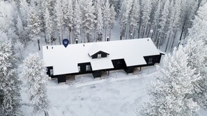 Eine schneebedeckte Lodge mit symmetrischer Dachlinie, mehreren Fenstern und einem zentralen Schornstein.