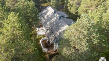 Una casa rodeada de un bosque frondoso, con una terraza visible y una chimenea.