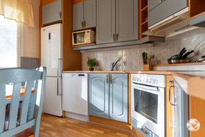 Eine kleine Küche mit Kühlschrank, Mikrowelle, Backofen und Spüle mit Wasserhahn.