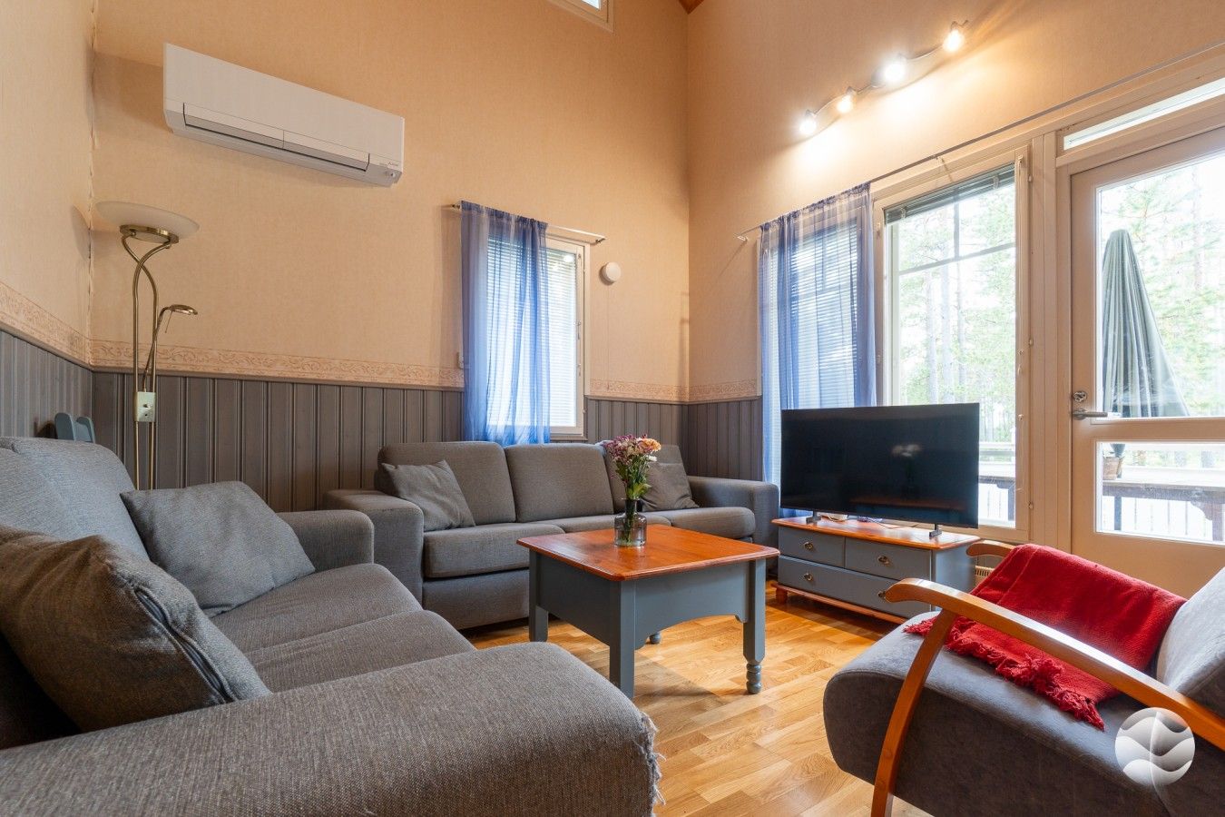 Olohuone, jossa on sohva, sohvapöytä, televisio ja ikkuna, jossa on verhot.