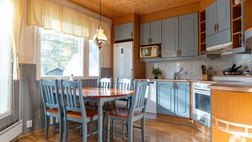 Een keuken met houten kastjes, een eettafel met stoelen en een hanglamp.