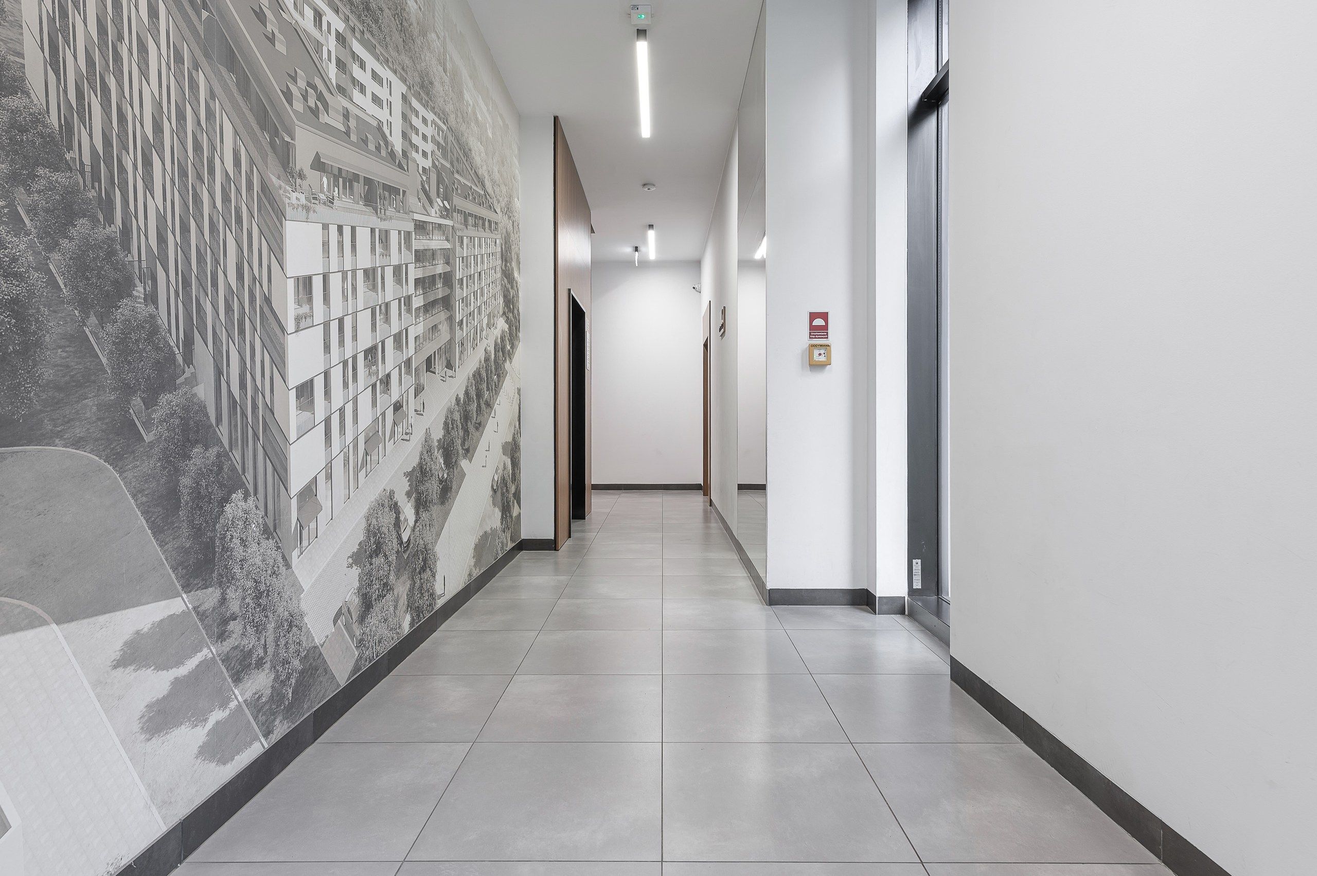 A corridor with a tiled floor, a large wall mural, and a door with a sign.