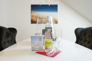 A table with a bottle of wine, a glass, a welcome card, and a red napkin. - Niendorf Residential Complex, Apartment 7 (Niendorf)