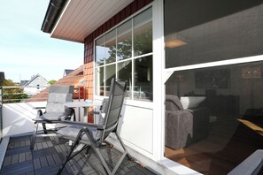 A modern outdoor seating area with a table and chairs, a large window, and a view of the surrounding neighborhood. - Niendorf Residential Complex, Apartment 7 (Niendorf)