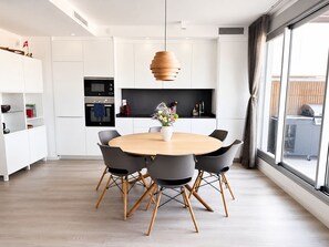 A modern kitchen with white cabinets, a round wooden dining table, and black chairs. - RDR557- Penthouse w. Scenic Views | Sleeps 6 (Estepona)