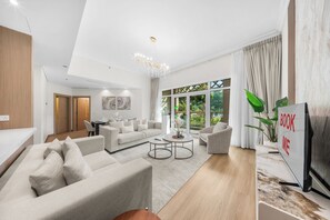 Una sala de estar moderna con un conjunto de sofá, una mesa de centro y un mueble de televisión con un cartel que dice 'BOOK ME'.