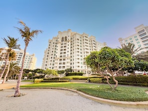 Ein Hochhaus-Hotel mit zahlreichen Balkonen, umgeben von gepflegter Bepflanzung und Palmen.