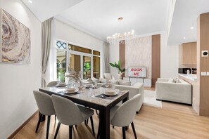 Un espace repas moderne avec une table en marbre, des chaises à revêtement gris et un lustre.