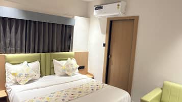 A modern hotel room with a large bed, a green sofa, a ceiling fan, and an air conditioning unit.