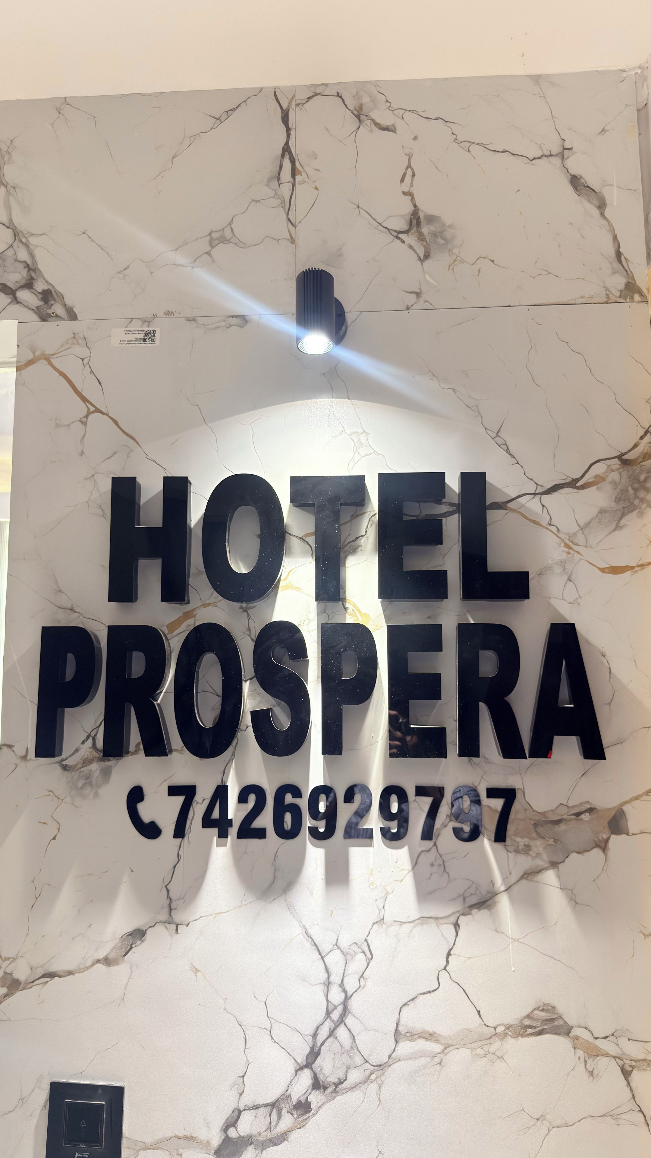 A marble wall with the text 'HOTEL PROSPERA' and a phone number.