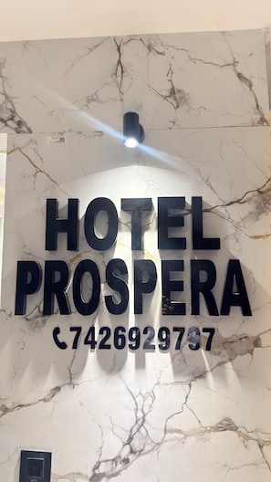 A marble wall with the text 'HOTEL PROSPERA' and a phone number.