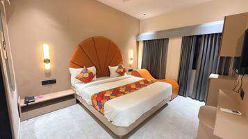 A hotel room with a large bed, a bedside table, a TV, and a curtain.