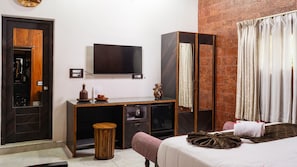 Habitació d'hotel amb llit, escriptori amb televisió, armari i mirall.