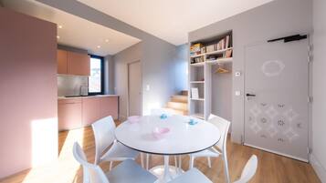 Une cuisine moderne avec une fenêtre, un coin repas comprenant une table ronde et des chaises, ainsi qu’une bibliothèque.
