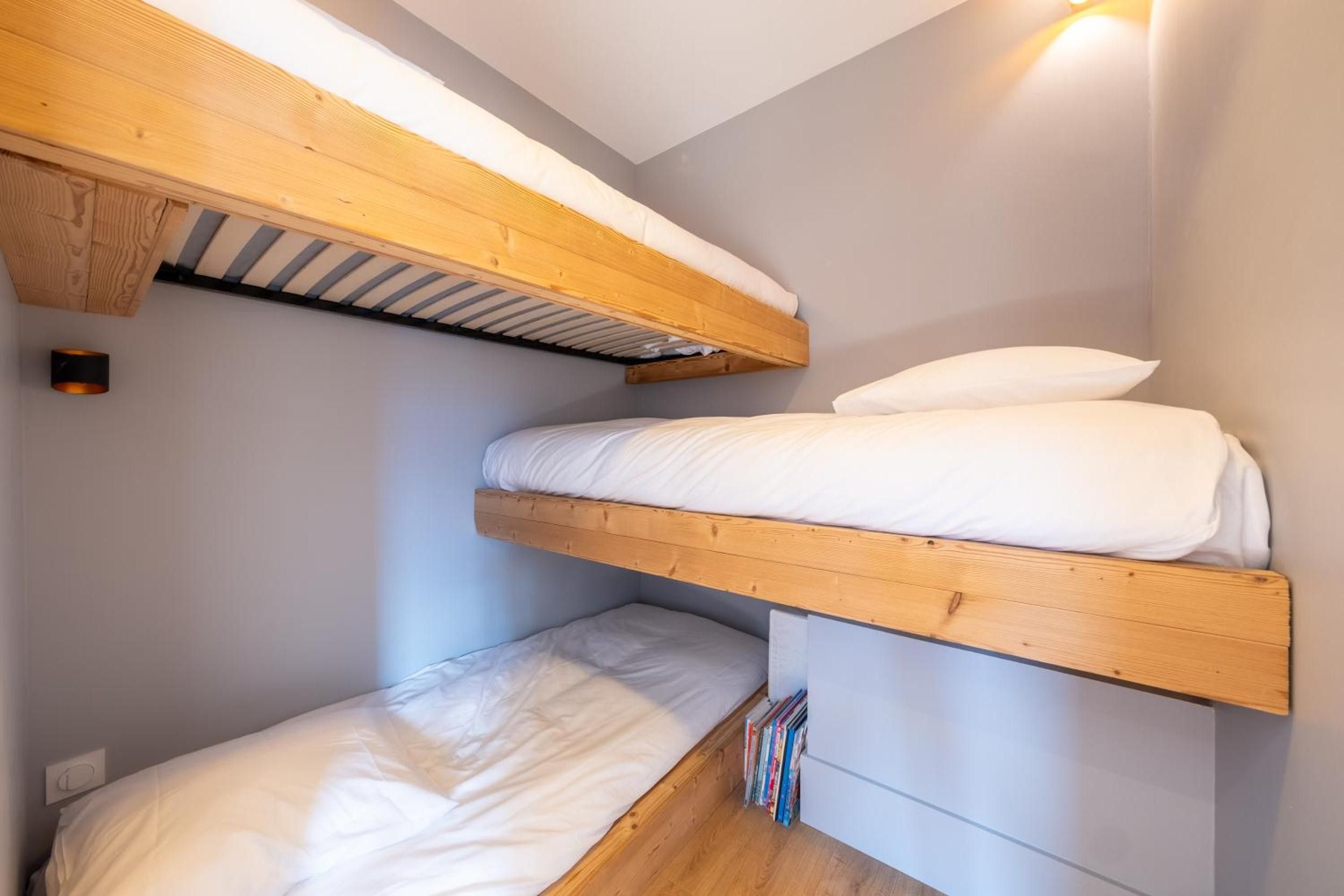 Un lit superposé avec des têtes de lit en bois et une literie blanche.