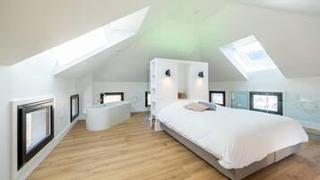 Una camera da letto moderna con finestra sul tetto, un letto grande, una vasca idromassaggio integrata e un box doccia in vetro.