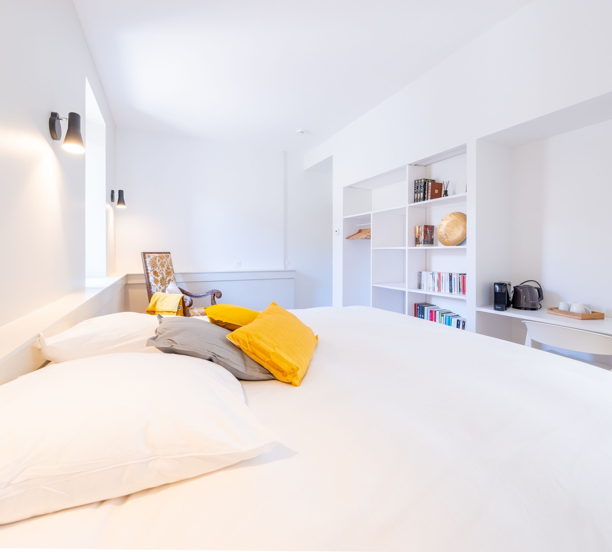 Une chambre moderne avec un grand lit, une table de chevet, une bibliothèque et un bureau avec un ordinateur.
