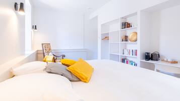Une chambre moderne avec un grand lit, une table de chevet, une bibliothèque et un bureau avec un ordinateur.