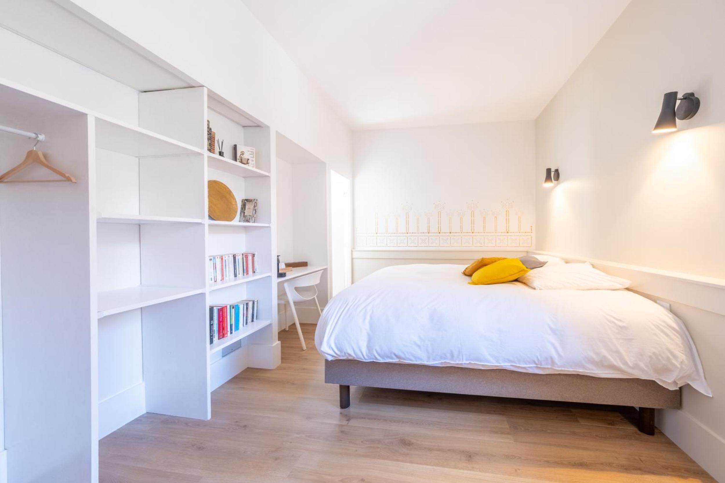 Une chambre à coucher avec un lit, une armoire blanche et un bureau.