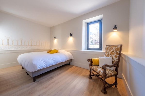 A bedroom with a bed, a chair, a window, and wall-mounted lights. - Room 'Chambre La Poudriere' with Mountain View (Saint-Jean-de-Maurienne)