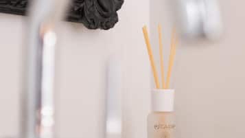 A bathroom sink with a modern faucet and a bottle of Escape brand reed diffuser.