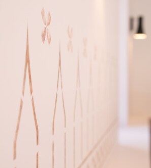 Un couloir orné d’une série de lignes verticales et éclairé par une source de lumière située à droite.