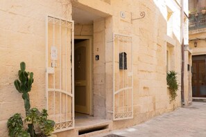 A building with a narrow street, a door with a metal gate, and a cactus plant. - Apartment 'Calcarìa Suite - 1' with Shared Terrace, Wi-Fi and Air Conditioning (Lecce)