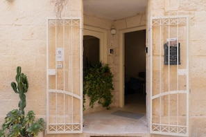 A building entrance with a metal gate, a cactus plant, and a door with a number. - Apartment 'Calcarìa Suite - 2' with Shared Terrace, Wi-Fi and Air Conditioning (Lecce)