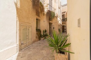 A narrow alleyway with stone pavement, a metal gate, and potted plants. - Apartment 'Calcarìa Suite - 2' with Shared Terrace, Wi-Fi and Air Conditioning (Lecce)