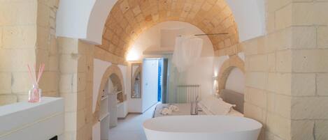 A modern bathroom with a large freestanding bathtub, a mirror, and a shower area.