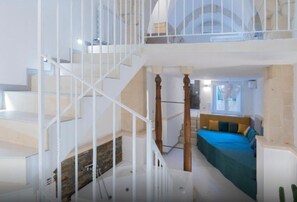 A multi-level interior with a staircase, a bed with blue bedding, and a window with natural light. - Apartment 'Calcarìa Suite - 3' with Shared Terrace, Wi-Fi and Air Conditioning (Lecce)