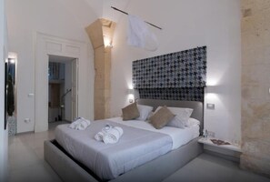 Een moderne slaapkamer met een groot bed, een hoofdbord met een patroon en een klein nachtkastje met een lamp.