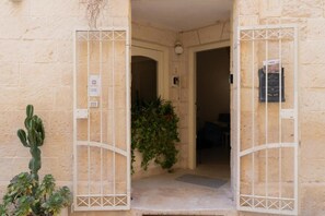 A building entrance with a metal gate, a cactus plant, and a door with a number. - Apartment 'Calcarìa Suite - 3' with Shared Terrace, Wi-Fi and Air Conditioning (Lecce)